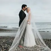 Los novios en la playa con el velo al viento